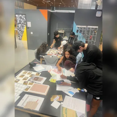 Students at IVA High work together on a project. They are grouped around tables that are covered in papers and tools.