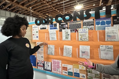 A student at IVA High shares her learning during the Exhibition of Learning. She is standing in front of a display that is labeled Our Constitution.