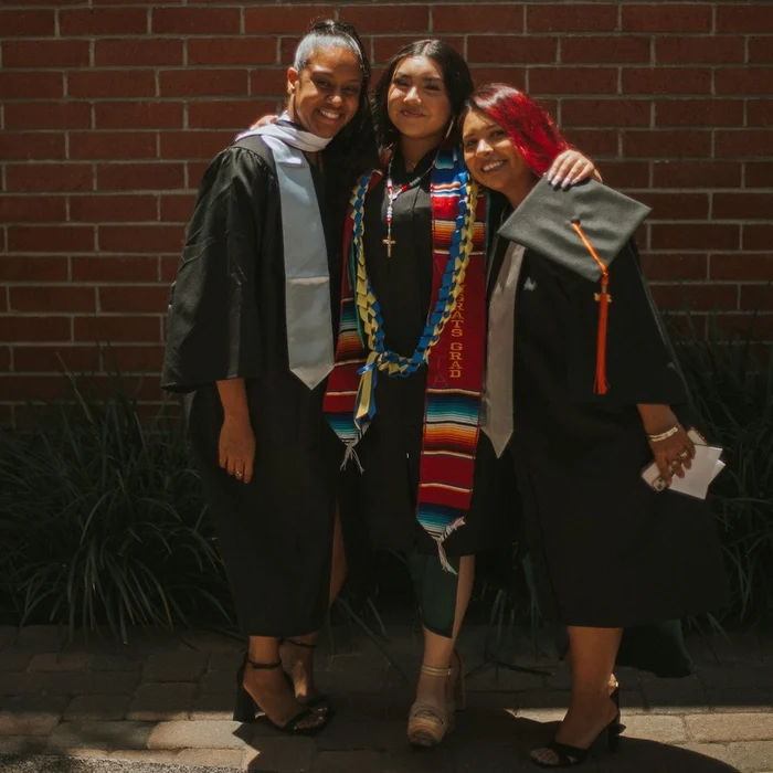 3 people in colorful graduation caps and gowns