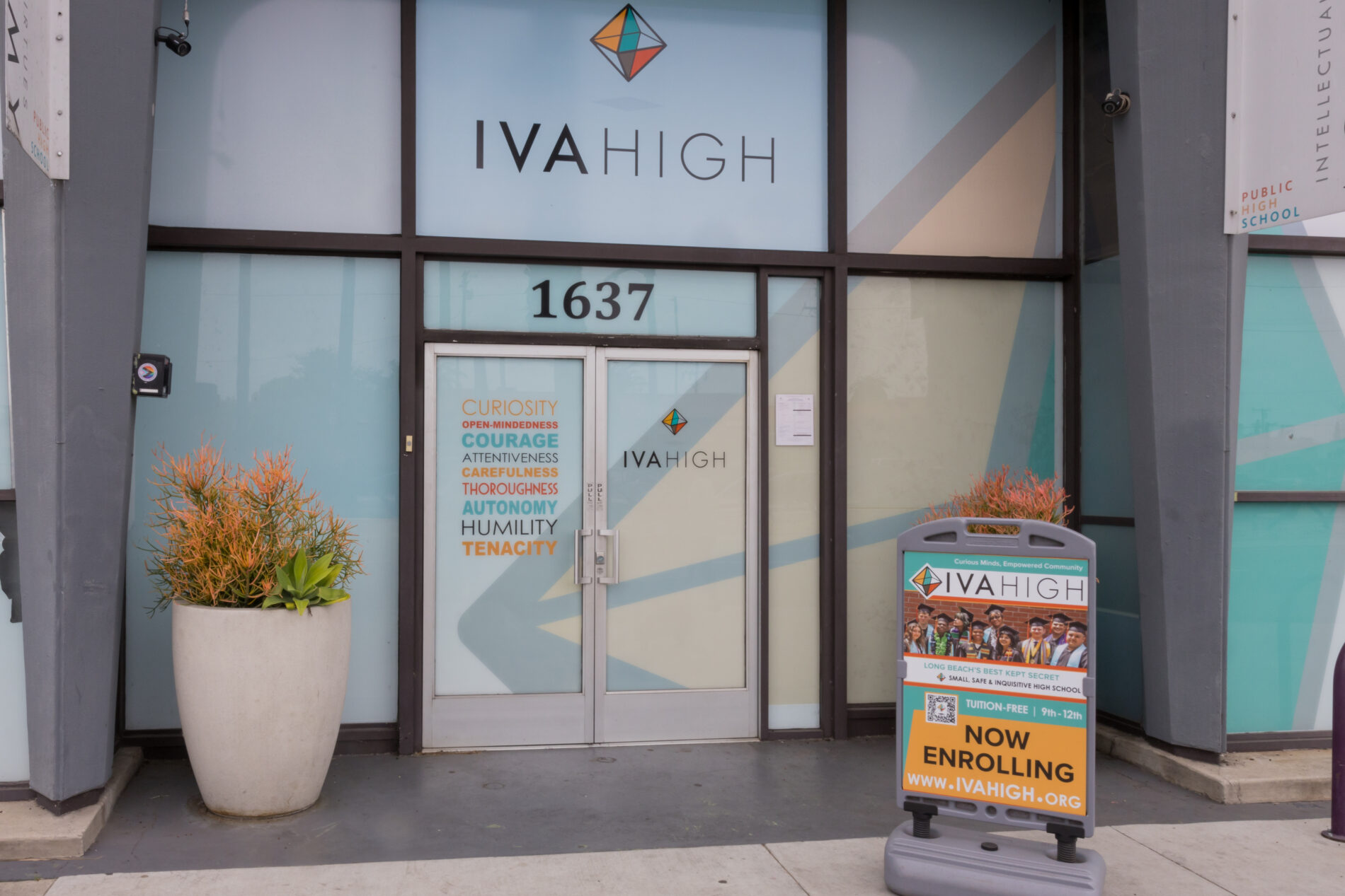 The front entrance of IVA High is brightly colored and a sign reads You Belong Here, Now Enrolling 9-12