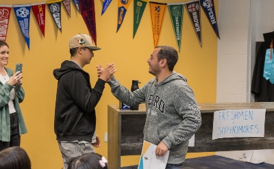 WhyChooseIVA_IVA High Award High Five A student and teacher give each other high five and teacher is holding a certificate