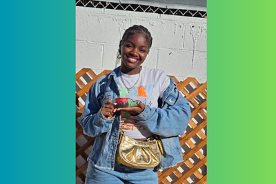 A student at IVA High stands outside and smiles as she holds a plant from a science experiment.