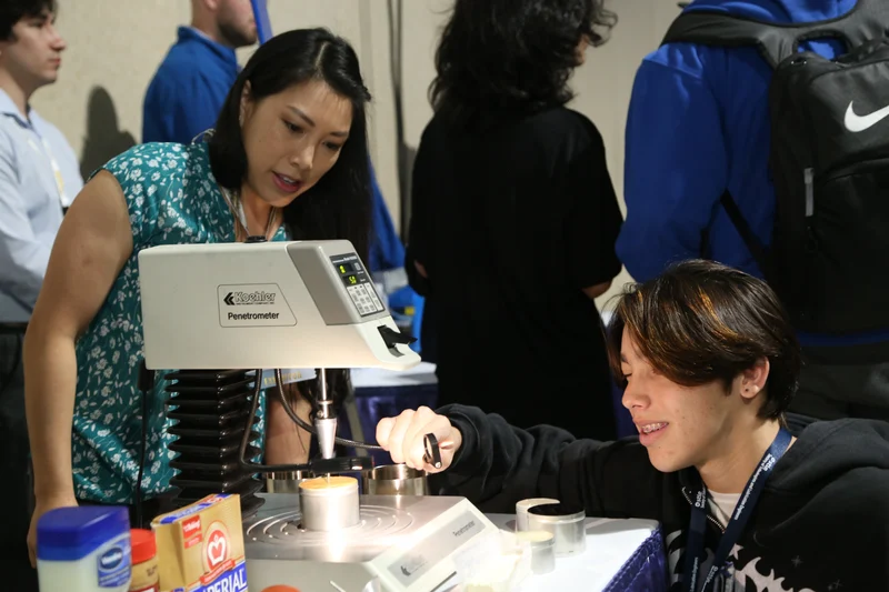 An IVA High student works with a penetrometer during a STEM camp. An adult looks on from behind the machine.