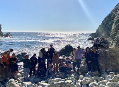 Students and teachers stand on the rocks at the California coast