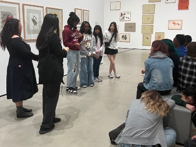 Students stand and sit in the museum