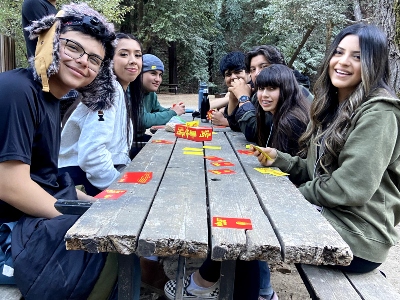 Students sit at picnic table playing a card game