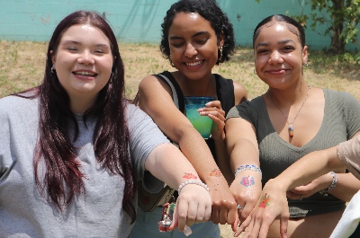 3 students at IVA High show off temporary tattoos on their hands and wrists. They are outdoors.