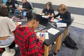 Students at IVA High work on projects at a table.