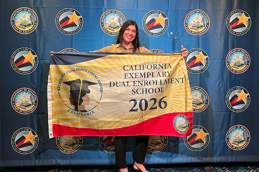 Summer Sanders, founder of IVA High in Long Beach, stands behind a banner that reads California Exemplary Dual Enrollment School 2026