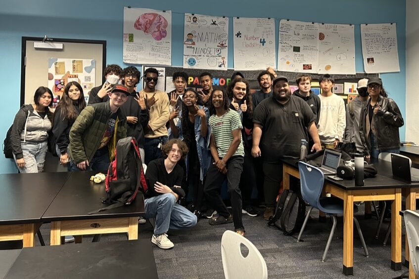 A group of students at IVA high in long beach gather together for a photo in a classroom.