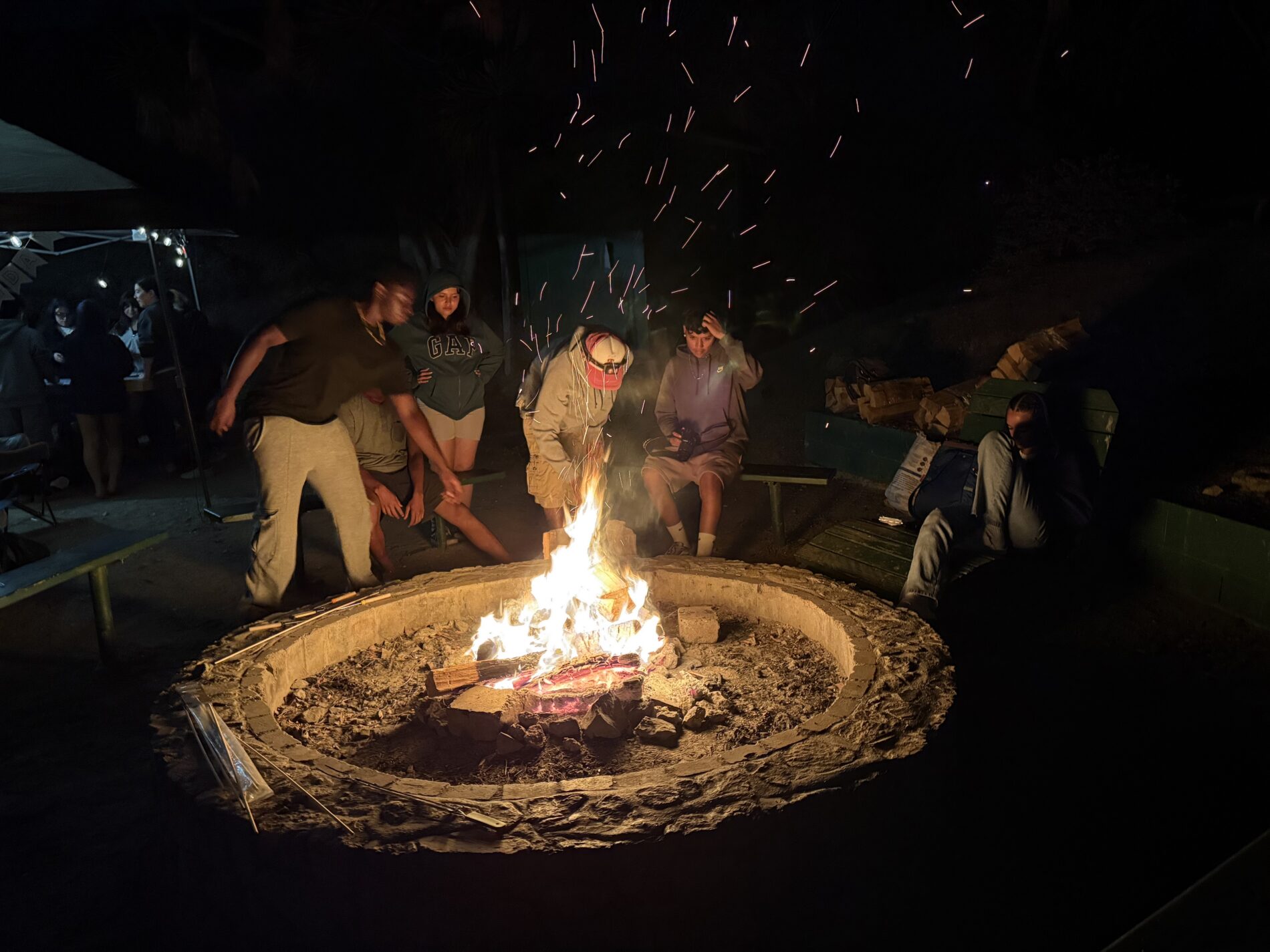 seniors from IVA High sit around an outdoor campfire pit