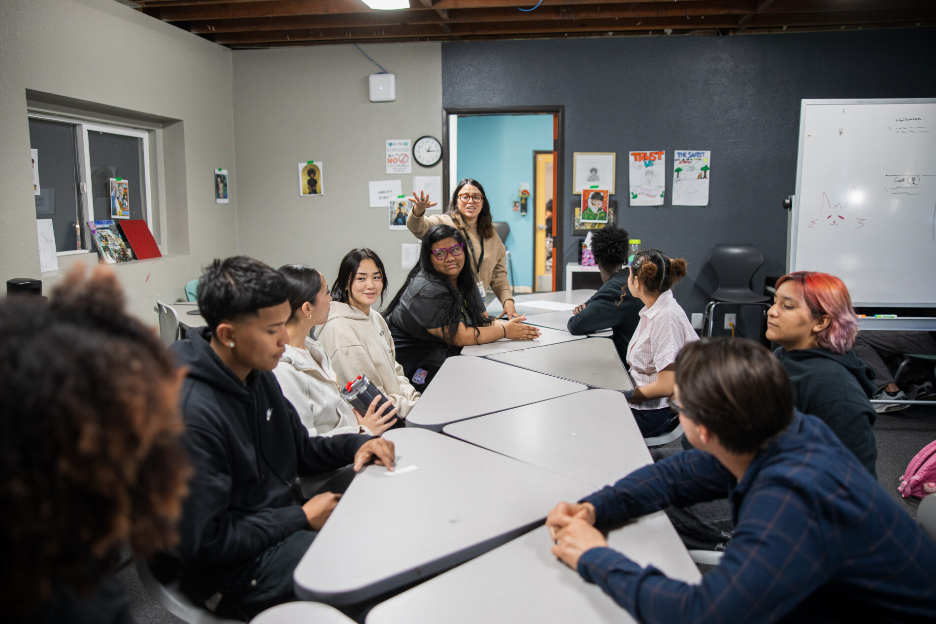 students and staff at IVA High in Long Beach sit around a long group of tables in a classroom
